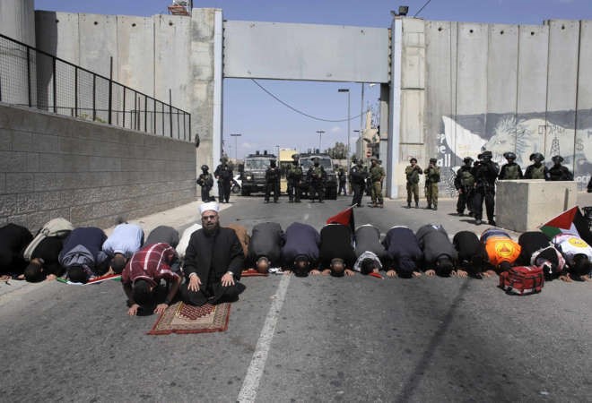  فلسطينيون يؤدون صلاة الجمعة امام نقطة تفتيش اسرائيلية قرب بيت لحم بالضفة الغربية امس رويترز 