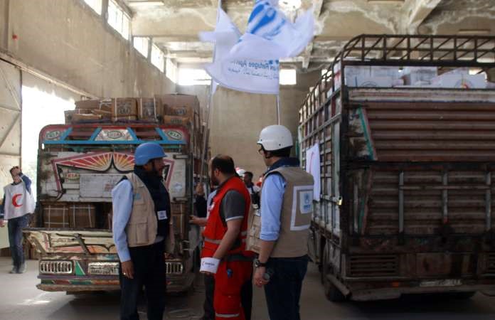 متطوعو الهلال الاحمر ومفوضية اللاجئين التابعة للامم المتحدة لدى وصولهم الى نقطة كراج الحجز في حي بستان القصر في حلب امس حاملين المساعدات افپ
