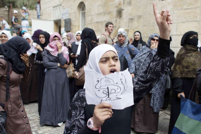 فتاة فلسطينية تحمل ورقة مكتوبا عليها الاقصى في خطر اثناء انتظارهاحتى تسمح لها قوات الاحتلال بدخولهافپ
