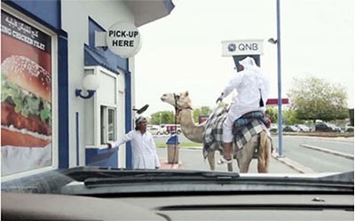 بالفيديو... قطري يمتطي الجمل وينتظر في الطابور المخصص للسيارات لاستلام وجبة "برغر" 