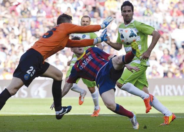 نجم برشلونة ليونيل ميسي يسدد الكرة وسط تدخل من حارس مرمى خيتافي جوليو سيزار 