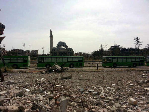 صورة بثها ناشطون للحافلات التي اقلت ثوار المعارضة لدى خروجها من حي الخالدية في حمصويبدو مسجد خالد بن الوليد المدمر 