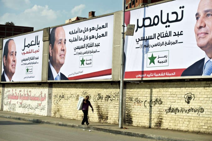 مصري يمر تحت ملصقات دعائية للمرشح الرئاسي عبد الفتاح السيسي في القاهرة امس افپ