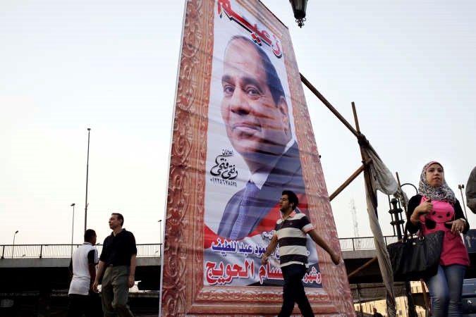 مصريون يمرون بالقرب من لافتة عملاقة داعمة للمرشح الرئاسي عبد الفتاح السيسي في القاهرة امس افپ