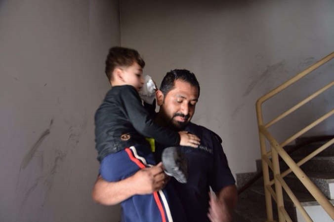رجل اطفاء يخلي احد الاطفال من البناية بعد اخراجه من الشقة﻿