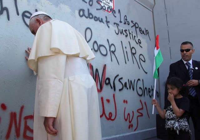 بابا الفاتيكانيقوم بوقفة رمزية عندالجدار العازل بجانب عبارة تشبه الفلسطينيين بالمعتقلين في معسكرات النازية في وارسو امس رويترز 
