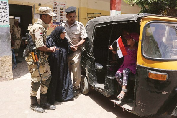 جنديان مصريان يساعدان مسنة عقب الادلاء بصوتها في الانتخابات الرئاسية امس رويترز