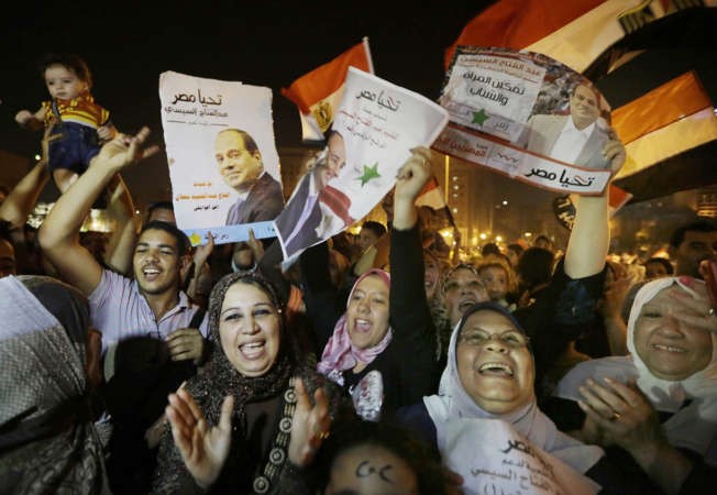  مصريون يرفعون صورا للمشير السيسي خلال الاحتفال بفوزه بالرئاسة بميدان التحرير امس 	 اب ﻿