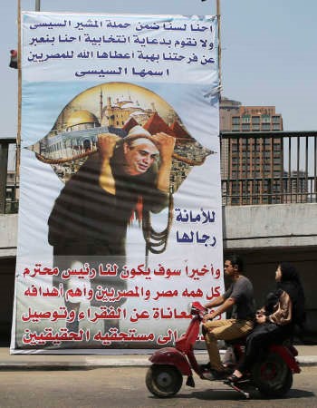 مصريان يمران بدراجة بخارية امام لوحة كبيرة داعمة للمشير عبدالفتاح السيسي امس رويترز