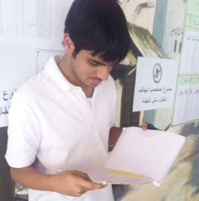 احد الطلبة يستذكر دروسه بجانب لوحة التحذير من دخول الهواتف الى قاعة الاختبار