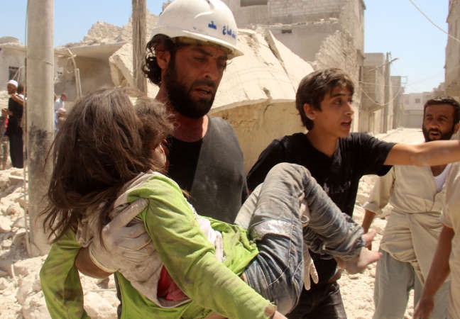 عمال انقاذ يسعفون طفلة اصيبت في غارة جوية على حي المرجة في حلب امس افپ