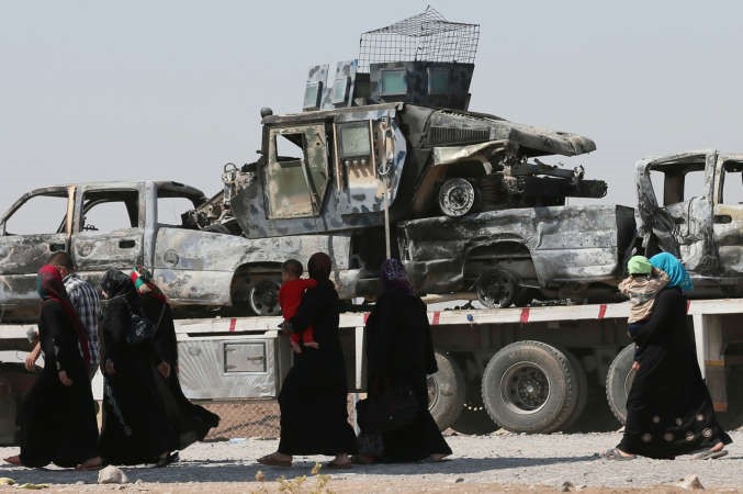 نازحون عراقيون من محافظة نينوى يمرون بجانب اليات مدمرةلدى وصولهم الى الحمدانية قرب اربيل امسافپ
