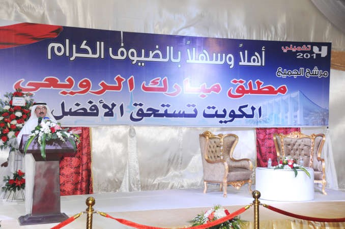 الرويعي متحدثا ويبدو شعاره الانتخابي
