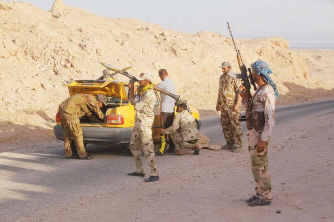 متطوعون عراقيون يفتشون احدى السيارات خلال تامينهم الطريق بين كربلاء والنجف امس الاولرويترز 
