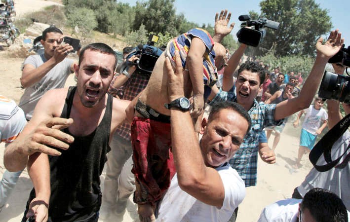 فلسطينيون يحملون طفلا قتلته احدى الغارات الاسرائيلية على غزةامس 	رويترز ﻿