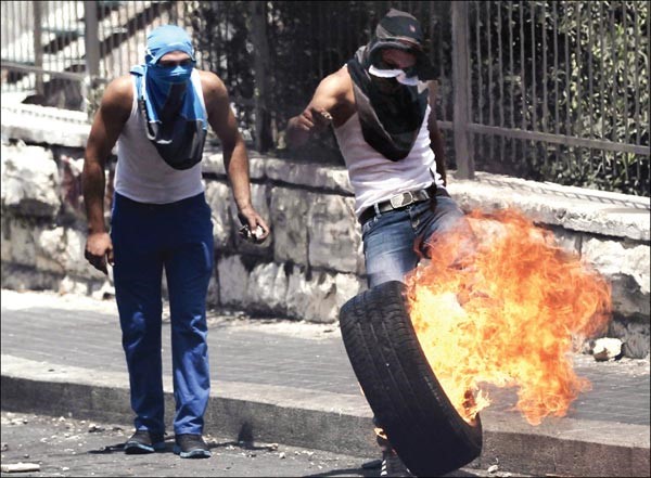 فلسطينيان يقذفان اطارا مشتعلا باتجاهالقوات الاسرائيلية خلال المواجهات بالقدس الشرقية امس افپ