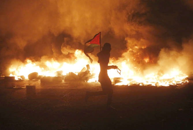 شاب فلسطيني يرفع علم بلاده خلال المواجهات العنيفةمع قوات الاحتلال عند معبر قلنديا امس الاول رويترز 