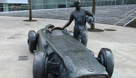 ويوجد تمثال من البرونز خارج متحف مرسيدس، يصور بطل العالم لسباقات F1 خوان مانويل فانجيو، والذي فاز خمس مرات، وهو يقف بجوار سيارته W196 والتي صنعت في العام 1954