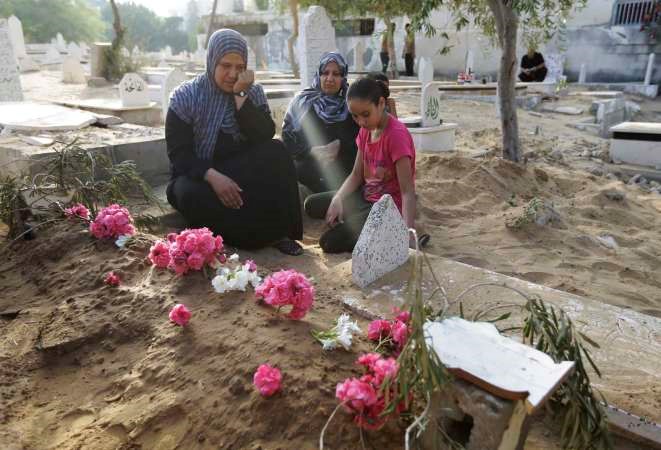 سيدة فلسطينية تزور قبر ولدها في اول ايام العيد بعد ان قتل في غارة اسرائيلية على قطاع غزة	اپ﻿