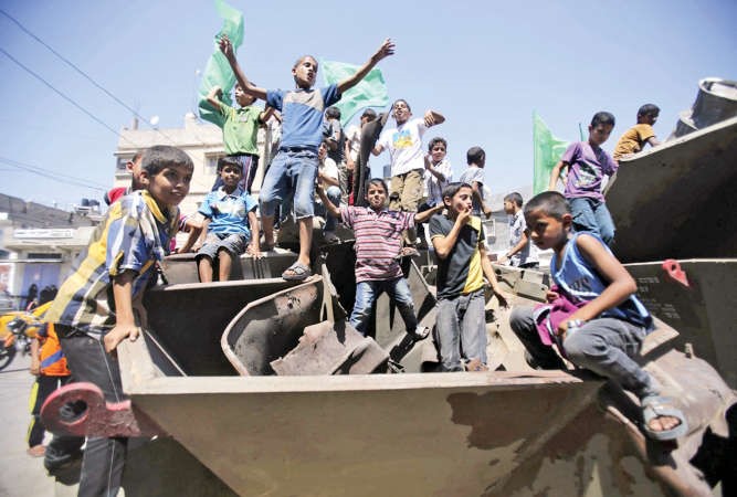 اطفال فلسطينيون يلوحون باعلامحماس من فوق مدرعةخلفتها القوات الاسرائيلية بعد انسحابهافي خان يونس امسرويترز ﻿