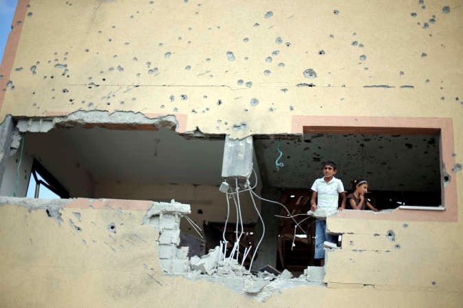طفلان فلسطينيان ينظران من منزلهما المتضرر جراء العداون الاسرائيلي على غزة رويترز