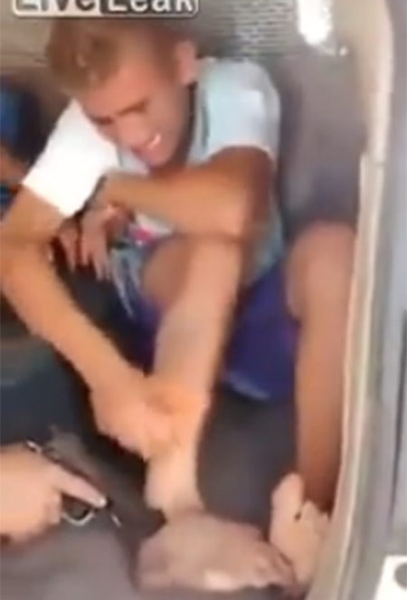 بالفيديو.. شرطي يهدد صبي بالمسدس لإزالة وشم على ساقه