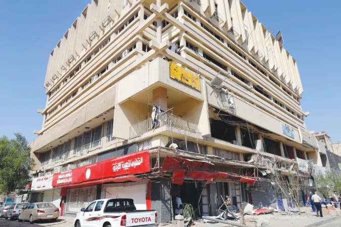 عراقيون يعاينون الاضرار الناجمة عن انفجار سيارة مفخخة في شارع السعدون وسط بغداد امس 	رويترز﻿