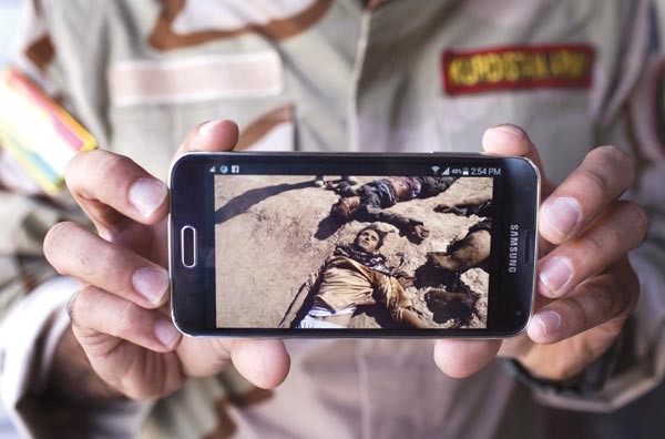 جندي كردي يعرض صورا لما قال انها جثث عناصر من داعش قتلوا في معارك مع البشمركة 	افپ