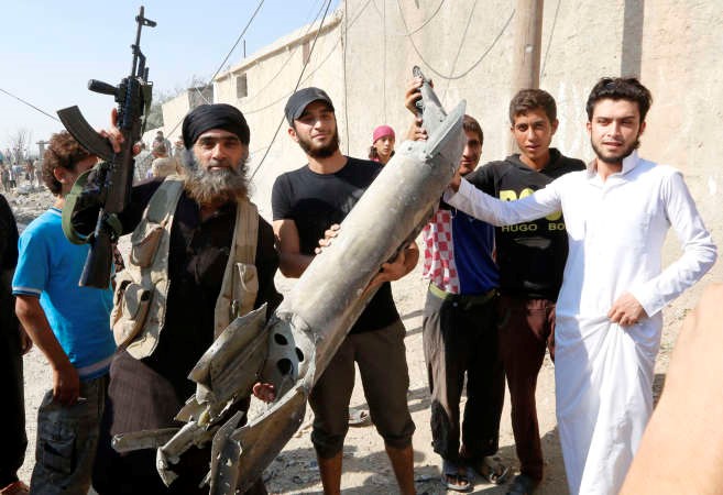 احد مقاتلي داعش يحمل اجزاء من حطام طائرة قال التنظيم انه اسقطها في الرقةامس رويترز
