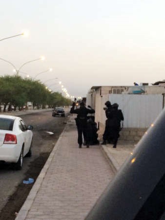 رجال الامن يحتمون من الطلقات النارية باحد المنازل