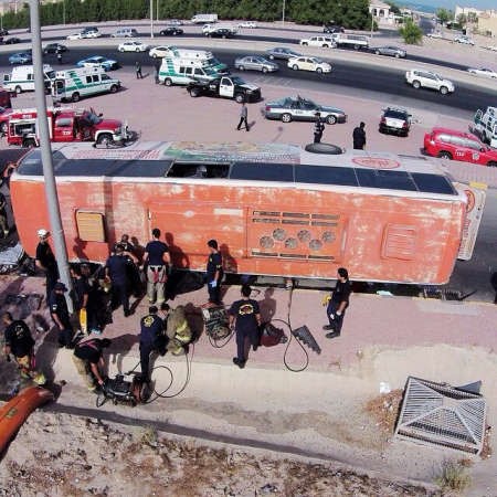 رجال الاطفاء ودوريات الامن في موقع الحادث وتبدو الحافلة كما انقلبت على جانب الطريق ﻿