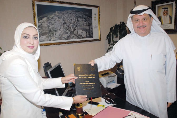 عيسى الكندري يتسلم نسخة لرسالة الماجستير من علية الكندري ﻿