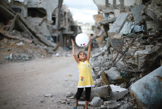 فتاة فلسطينية تلعب بالبالون بالقرب من منزل عائلتها المدمر نتيجة العدوان الاسرائيلي الاخير على غزة