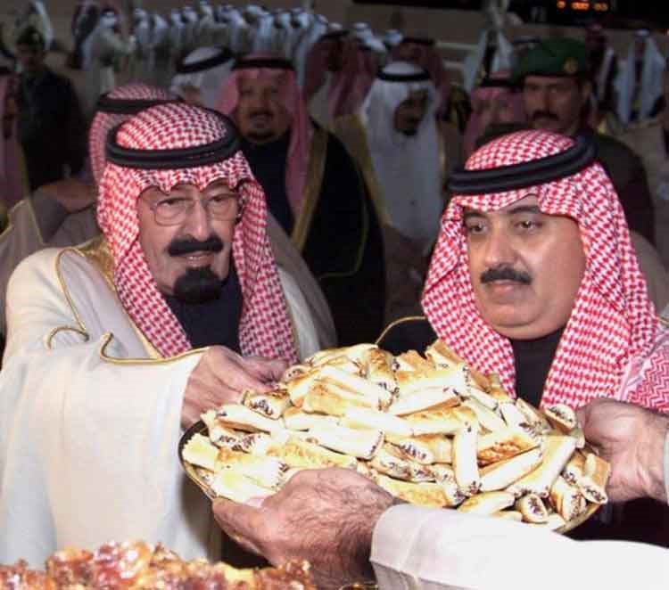 الملك عبد الله يتناول التمر و بجواره ابنه سمو الامير متعب بن عبد الله اثناء حفل الجنادرية عام 2002