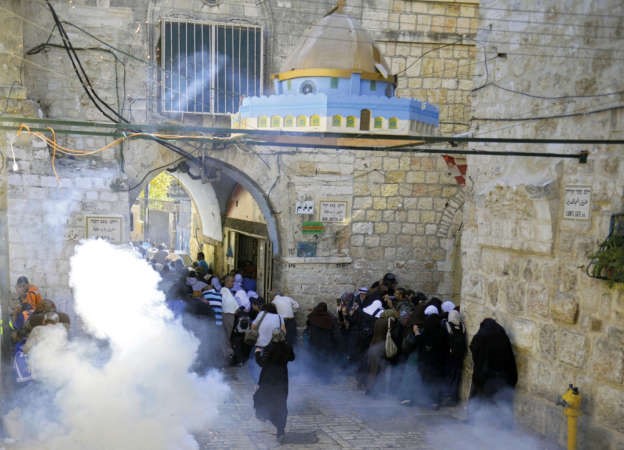 فلسطينيون يحتمون منقنابل الغاز المسبل للدموع التي اطلقتها قوات الاحتلال بمحيط الاقصى امس 	اپ ﻿
