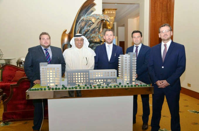 ترنان ديلون وجو ماكورماك يتوسطهما اعضاء من الشركة بالكويت وامامهم مجسم للمباني في بريطانيا﻿