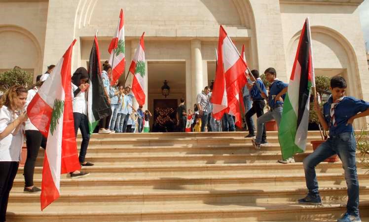 طلاب يحملون الاعلام الفلسطينية واللبنانية في استقبال المعلم على مدخل كاتدرائية مار نقولا في الاشرفية