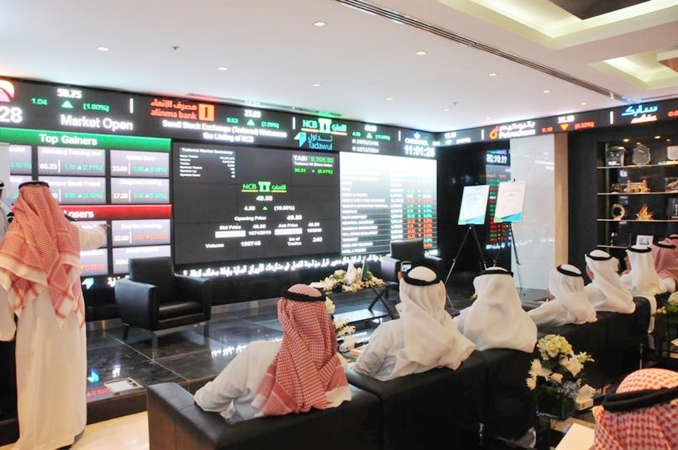 السعوديون يتهافتون على سهم الاهلي التجاري اكبر بنك سعودي مع ادراجه امس وفي الصورة متداولون يراقبون حركة السهم الذي قفز بالحد الاعلى