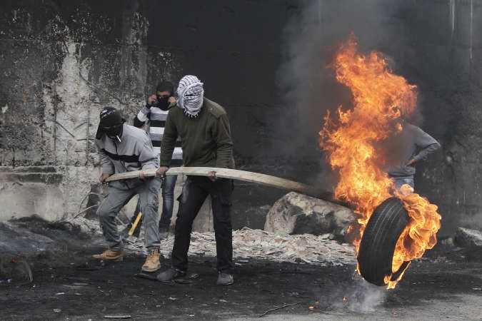متظاهرون فلسطينيون يشعلون اطارا خلال مواجهات مع قوات الاحتلالبالضفة امس افپ
