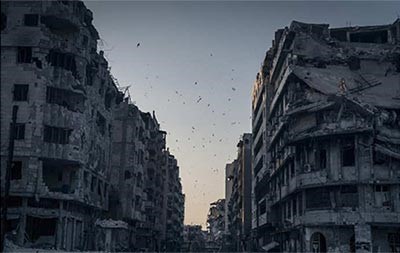 الموقع سوريا - حمص، المصور سيرجي بونوماريف فئة الاماكن، صورة Destroyed Homs، تظهر المنازل المحطة في مدينة حمص السورية، يقول المصور انه توجد العديد من المناطق في المدينة لا تشهد فيها اي حركة، ولكن فجاة ظهر سرب من الطيور ليضفي القليل من الحياة على