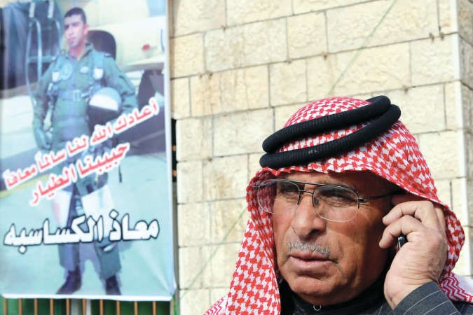 والد الطيار الاردني معاذ الكساسبة يقف الى جانب ملصق ابنه في تجمع لعائلته في الكرك جنوب عمان امس 	افپ﻿