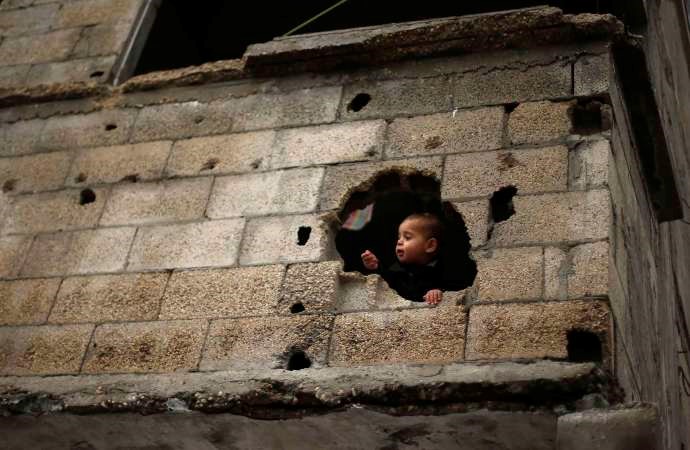طفل فلسطيني يطل من ثقب في منزل عائلته المتضرر جراء القصف الاسرائيلي على غزة في يوليو واغسطس الماضيينرويترز﻿