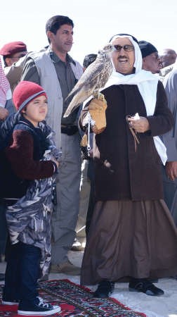 صاحب السمو يحمل صقرا خلال زيارته الى القرية