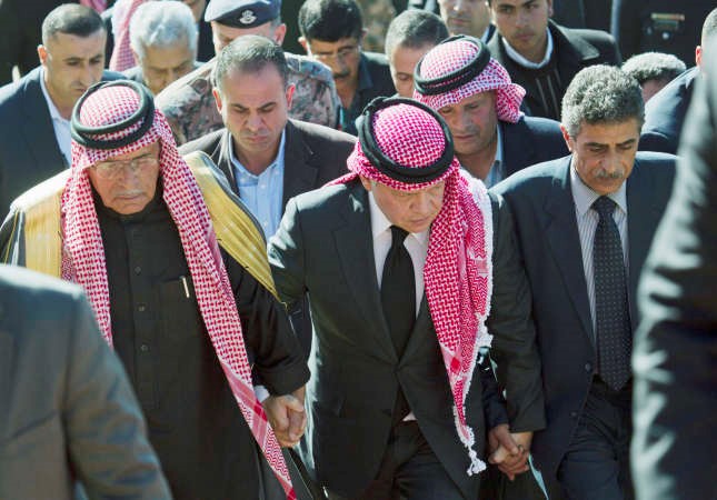 الملك عبد الله الثاني متوسطا والد الطيار معاذ الكساسبة وعمهخلال زيارته لديوان العائلة لتقديم العزاءاپ