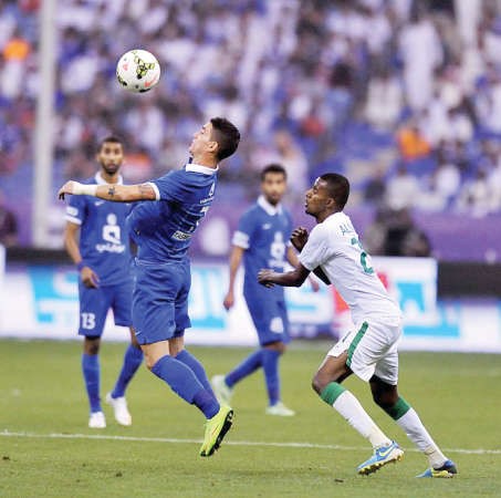 محترف الهلال تياغو نيفيز يسيطر على الكرة بمضايقة من مدافع الاهلي ﻿