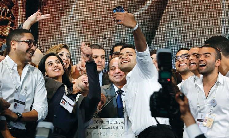 الرئيس المصري عبدالفتاح السيسي مبتسما وبعض الشباب المنظمين للمؤتمر الاقتصادي ياخذون صورة سيلفي معه وهو يلقي كلمته في اليوم الختامي لـ مصر المستقبل امس رويترز﻿