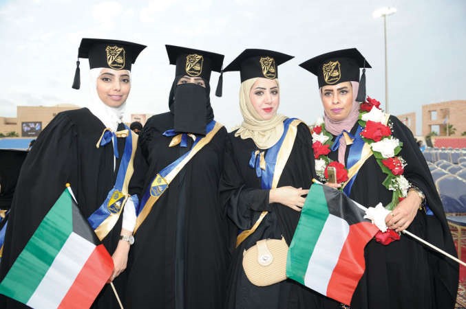 عدد من الخريجات يحملن اعلام الكويت
