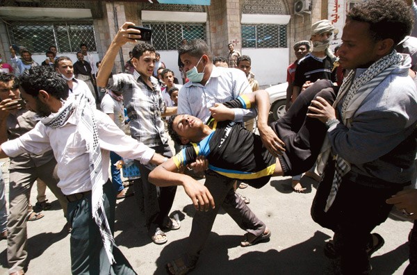 متظاهرون يحملون زميلا اصيب برصاص الحوثيين الحي خلال تفريقهم رويترز