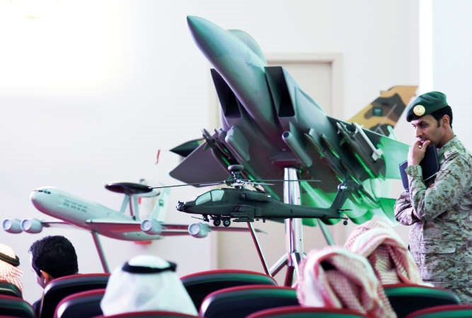 رجل امن سعودي يقف بجانب نسخة صغيرة من طائرة مقاتلة اماراتية مشاركة في عاصفة الحزم خلال المؤتمر الصحافي الذي يجرى يوميا لمعرفة نتائج العمليات امس الاول 	افپ﻿