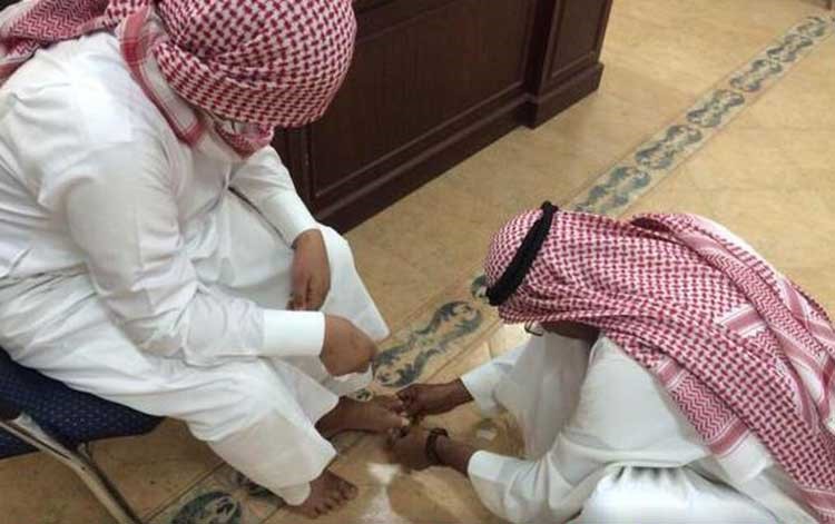 بالصور.. معلم على الأرض ويجلس أحد طلابه على كرسي لتضميد جرح بقدمه